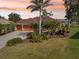 Charming home with a paver driveway, a lush lawn, tropical landscaping, and a two-car garage at 16137 Alcira Cir, Punta Gorda, FL 33955