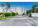 An exterior view of 'La Coquina' surrounded by lush greenery and palm trees under a clear blue sky at 2820 N Beach Rd # 101, Englewood, FL 34223