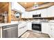 Modern kitchen featuring white cabinets, stainless steel appliances, rustic wood accents, and farmhouse sink at 2820 N Beach Rd # 101, Englewood, FL 34223