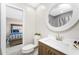 Neat and modern bathroom with a sleek vanity, round mirror, and adjacent bedroom for convenience at 5041 N Beach Rd # 1A And 1B, Englewood, FL 34223