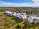 An aerial view showing condos and neighborhood amenities amidst lush greenery and ocean view background at 6610 Gasparilla Pines Blvd # 111, Englewood, FL 34224