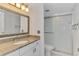 Bathroom with granite-look vanity top and tiled shower behind sliding glass doors at 6610 Gasparilla Pines Blvd # 111, Englewood, FL 34224