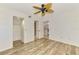 Bright bedroom with light walls, ceiling fan, wood-look floors, closet, and view of living area at 6610 Gasparilla Pines Blvd # 111, Englewood, FL 34224
