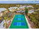 Aerial view of vibrant tennis courts, swimming pool, and yellow condos surrounded by beautiful trees at 6610 Gasparilla Pines Blvd # 111, Englewood, FL 34224