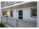 Apartment 133 shows a teal front door, small plants, and grey-stained wood balcony at 6800 Placida Rd # 133, Englewood, FL 34224