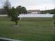 View of the backyard showcasing a green lawn, a white fence, and mature trees at 6998 Dabarsky Ave, North Port, FL 34291