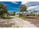 A single story home in the residential community surrounded by tropical landscaping and a gravel driveway at 7032 Duke St, Englewood, FL 34224