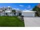 Inviting white home with a lush green lawn, featuring a 2-car garage and well-maintained landscaping at 709 Valencia Rd, Venice, FL 34285