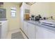 Bright laundry room featuring white cabinets, tile floors, and a window for natural light at 7237 Rum Bay Dr # 5022, Placida, FL 33946