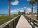 Scenic beach boardwalk with palm trees, leading to sandy shoreline and blue waters at 840 E 7Th St, Englewood, FL 34223