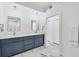 A modern bathroom with double sinks, white marble floors, and dark blue cabinets at 9203 Griggs Rd # 204, Englewood, FL 34224