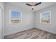 A bedroom with hardwood floors, two windows overlooking neighborhood, and modern ceiling fan at 9203 Griggs Rd # 204, Englewood, FL 34224