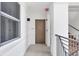 Well-lit hallway featuring a unit entrance, staircase access, and neutral decor at 9203 Griggs Rd # 204, Englewood, FL 34224