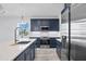 Bright kitchen with stainless appliances, blue cabinets, white counters, and a view from the window at 9203 Griggs Rd # 204, Englewood, FL 34224