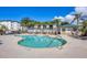 Gorgeous community pool with lounge chairs, lush palm trees, and nearby community building at 9203 Griggs Rd # A204, Englewood, FL 34224