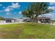 Exterior view of the home showing the backyard, lush lawn, and a large shade tree at 10075 Bay Ave, Englewood, FL 34224