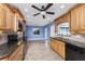 Spacious kitchen featuring wooden cabinets, granite countertops, and black appliances, with tile flooring and a ceiling fan at 10075 Bay Ave, Englewood, FL 34224