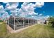 Backyard view of the screened pool enclosure and outdoor space with a shed and green lawn; perfect for entertaining at 10075 Bay Ave, Englewood, FL 34224