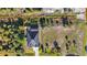 Aerial view displays a home with a screened-in pool area, manicured lawn, and verdant landscaping at 10498 Bay State Dr, Port Charlotte, FL 33981