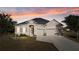 Charming single-story home with a well-manicured lawn and a two-car garage at sunset at 10498 Bay State Dr, Port Charlotte, FL 33981