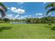 Lush backyard features vibrant green grass, mature trees, and serene pond views at 108 Fairway Rd, Rotonda West, FL 33947