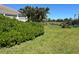 Spacious backyard with lush lawn, hedges for privacy, and a pond in the distance at 108 Fairway Rd, Rotonda West, FL 33947