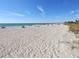 Wide sandy beach with clear blue water and scattered sunbathers under a sunny sky at 108 Fairway Rd, Rotonda West, FL 33947
