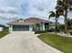 Charming single-story home with a two-car garage, a well-manicured lawn, and lush tropical landscaping at 108 Fairway Rd, Rotonda West, FL 33947