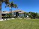 Inviting single-story home with lush landscaping, mature palm trees, and well-manicured lawn at 108 Fairway Rd, Rotonda West, FL 33947