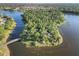 Picturesque aerial of a lush wooded island surrounded by a serene lake, accessible by a charming bridge at 11417 Okaloosa Dr, Venice, FL 34293