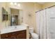 Well-lit bathroom with a vanity, toilet, and shower featuring a decorative curtain, offering a clean and functional space at 11417 Okaloosa Dr, Venice, FL 34293