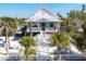Charming elevated beach house with white picket fence and lush tropical landscaping at 14 Palm Dr, Placida, FL 33946
