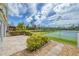 Backyard with patio and lawn features views of the tennis court and pond at 14281 Palm Ter, Port Charlotte, FL 33953