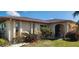 Well-manicured single Gathering home with red flowers, green shrubs and a sidewalk and green lawn at 171 Caddy Rd, Rotonda West, FL 33947