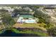 The community pool and tennis courts are seen from above, surrounded by lush green trees at 202 Silver Lake Dr # 203, Venice, FL 34292