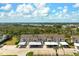 Aerial view of condo buildings with covered parking, trees, blue skies, and a well-maintained parking lot at 202 Silver Lake Dr # 203, Venice, FL 34292