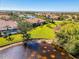 Aerial view of a home next to a pond in a lush, green community featuring lakes and mature trees at 2625 Wax Myrtle, Port Charlotte, FL 33953
