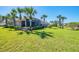 Expansive backyard with lush green grass and well-maintained landscaping and mature palm trees at 2625 Wax Myrtle, Port Charlotte, FL 33953