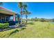 Lush backyard featuring palm trees, a screened lanai, and views of the surrounding green space and pond at 2625 Wax Myrtle, Port Charlotte, FL 33953