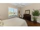 Relaxing bedroom with wood floors, ceiling fan, large window, and wooden dresser with decorative mirror at 2625 Wax Myrtle, Port Charlotte, FL 33953