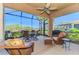 Screened lanai featuring wicker furniture, a ceiling fan, and views of a lake and landscaping at 2625 Wax Myrtle, Port Charlotte, FL 33953