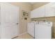 Laundry room featuring a washer and dryer, white cabinets, tile flooring, and a door to the outside at 2625 Wax Myrtle, Port Charlotte, FL 33953
