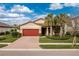Charming single-Gathering home with a brick driveway, red garage door, and well-manicured landscaping at 2628 Sherman Oak Dr, North Port, FL 34289