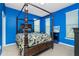 Elegant main bedroom with a dark wood canopy bed and striking blue walls at 2628 Sherman Oak Dr, North Port, FL 34289
