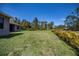 View of the spacious backyard with a lush green lawn, surrounded by trees and vegetation at 3284 Newmark St, North Port, FL 34291