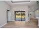 Open-concept living room with wood floors, tray ceiling and large sliding glass doors to the backyard at 3284 Newmark St, North Port, FL 34291