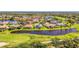 An aerial view shows the single Gathering homes surrounding a large pond on a golf course at 3574 Pennyroyal Rd, Port Charlotte, FL 33953