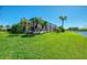 Expansive backyard with lush grass, mature palm trees, and a serene water view at 3574 Pennyroyal Rd, Port Charlotte, FL 33953