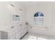 Bright bathroom with double vanity, tub, tiled floors, a vanity mirror, and a shuttered window at 3615 Pennyroyal Rd, Port Charlotte, FL 33953