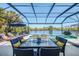 Covered patio with ample seating for outdoor dining, overlooking a sparkling pool and waterfront at 3615 Pennyroyal Rd, Port Charlotte, FL 33953